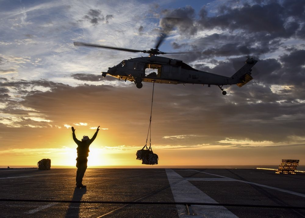 Helicopter lowering supplies onto a ship deck